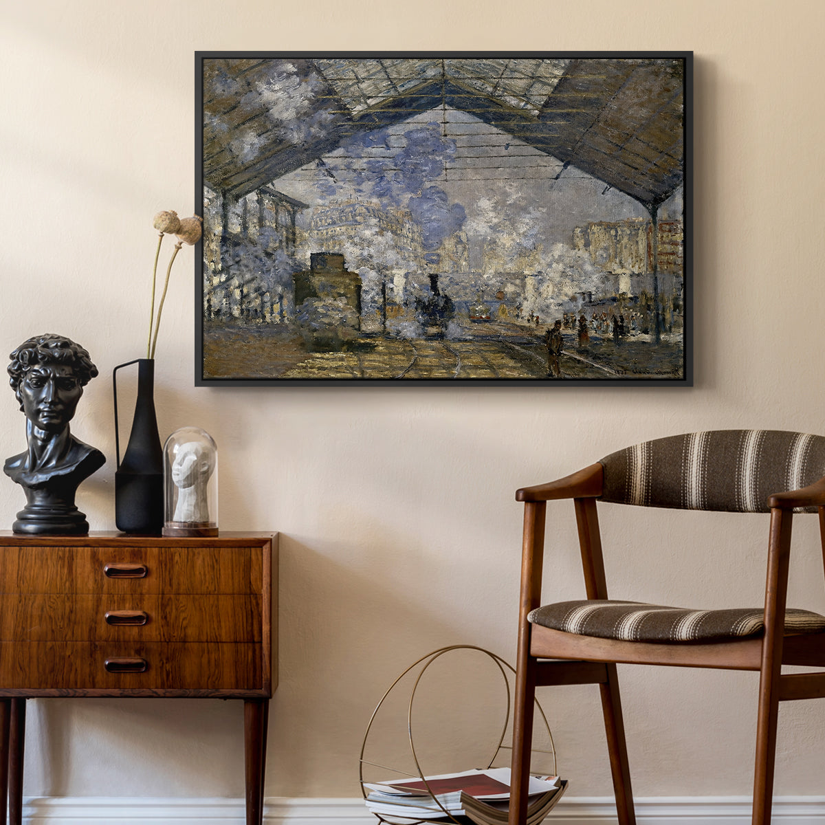 The Gare Saint-Lazare, 1877 by Claude Monet as a black floater framed canvas featuring an industrial interior with steam clouds and rail tracks, styled above a mid-century console in a contemporary living area.