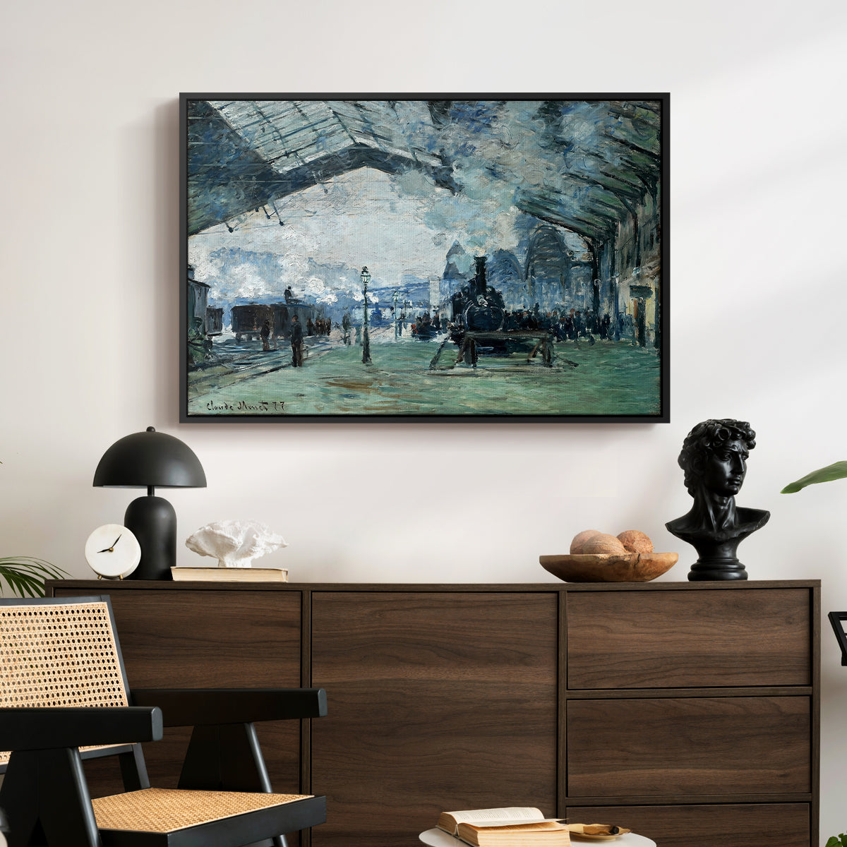The Saint-Lazare Station, 1877 by Claude Monet displayed in a black floater framed canvas above a dark wood credenza in an entryway.
