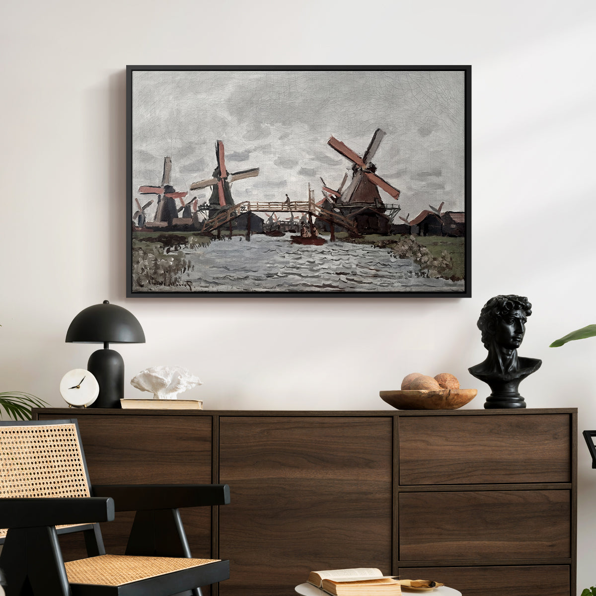 Windmills near Zaandam, 1871 by Claude Monet displayed in a black floater framed canvas above a dark wood credenza in an entryway.