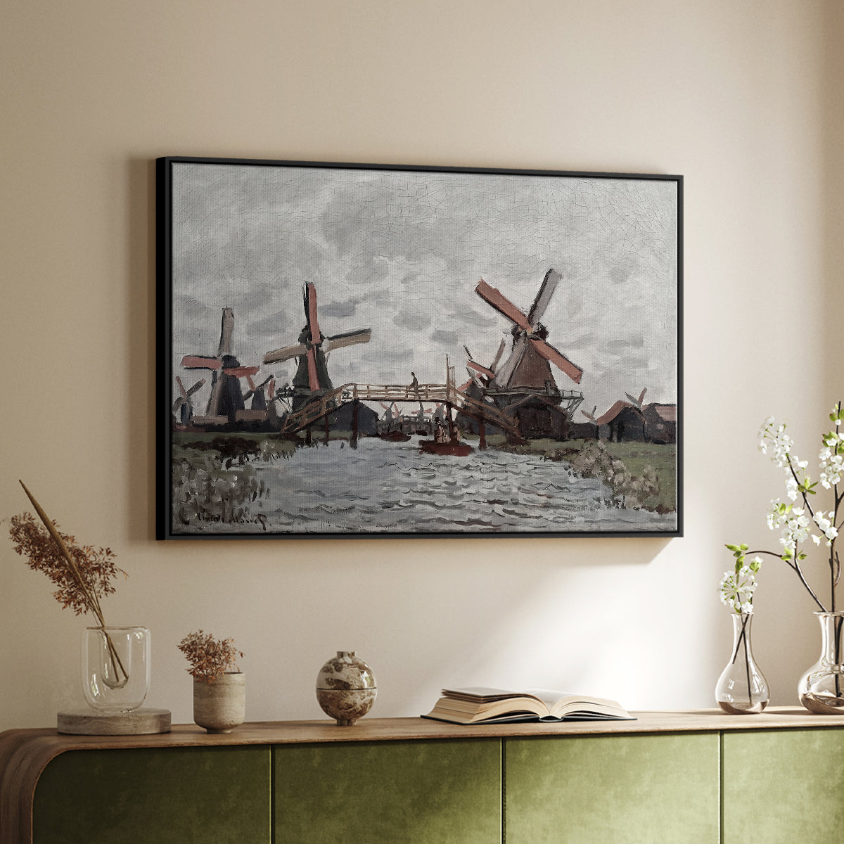 Black floater framed canvas of Windmills near Zaandam, 1871 by Claude Monet, featuring an impressionist view of Dutch windmills along riverbank above a sideboard in a softly lit hallway.