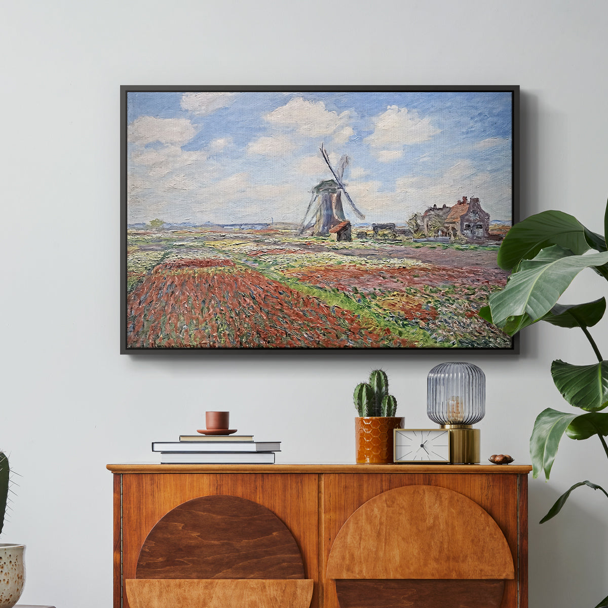 Tulip Fields with the Rijnsburg Windmill, 1886 by Claude Monet in a black floater framed canvas featuring colorful rows of tulip fields leading toward distant windmill, displayed above a wood console cabinet.