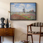 Tulip Fields with the Rijnsburg Windmill, 1886 by Claude Monet as a black floater framed canvas featuring an impressionist field of blooming tulips under bright sky, styled above a mid-century console in a contemporary living area.
