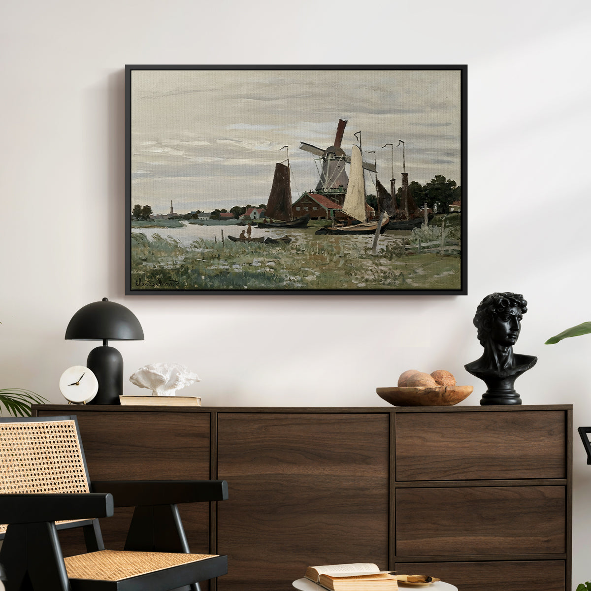 Windmill at Zaandam, 1871 by Claude Monet displayed in a black floater framed canvas above a dark wood credenza in an entryway.