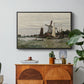 Windmill at Zaandam, 1871 by Claude Monet in a black floater framed canvas featuring a single windmill beside water with surrounding buildings and sky, displayed above a wood console cabinet.