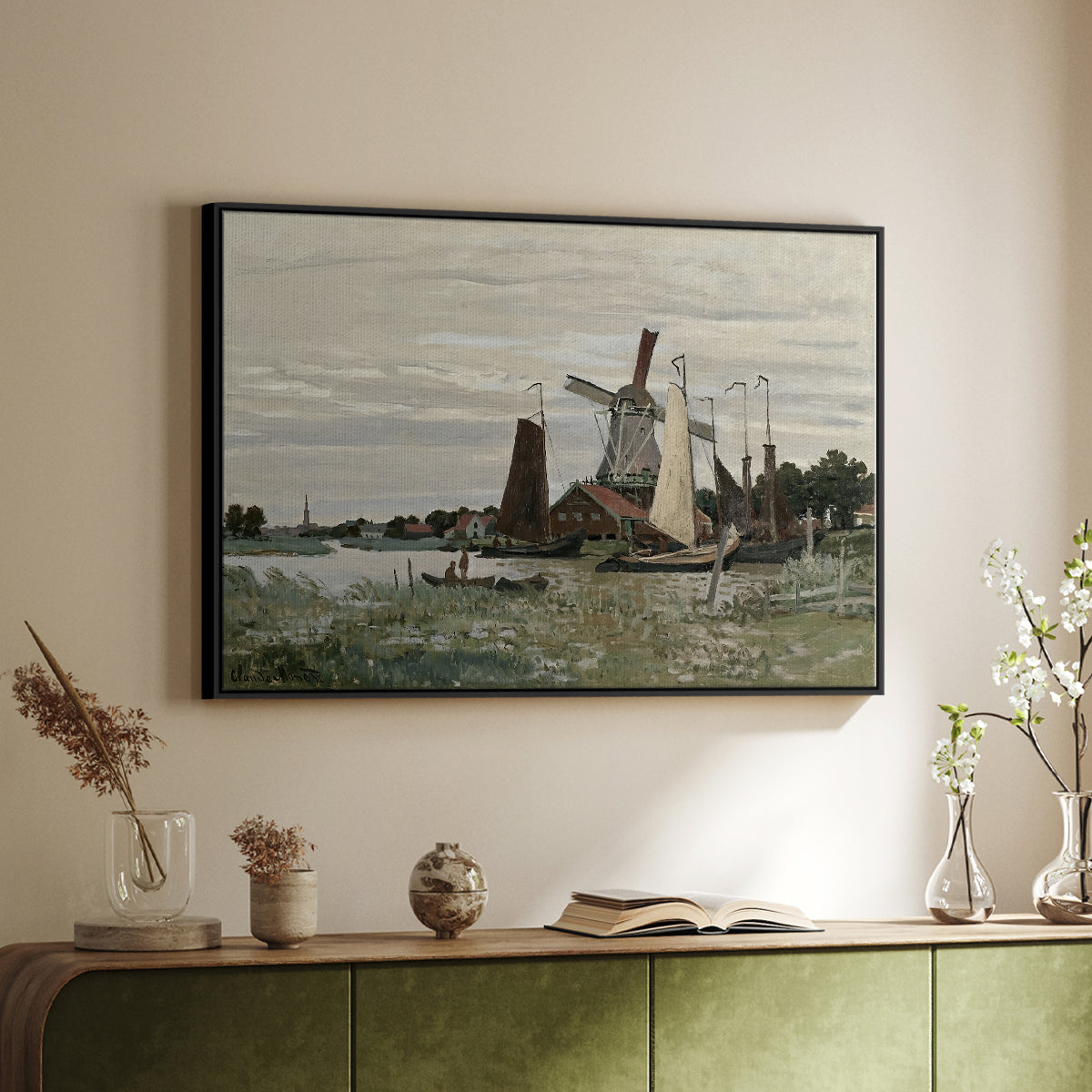 Black floater framed canvas of Windmill at Zaandam, 1871 by Claude Monet, featuring an impressionist depiction of windmill near riverbank above a sideboard in a softly lit hallway.