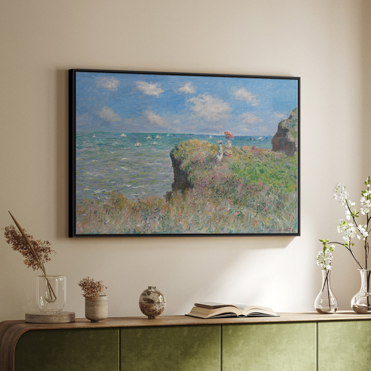 Black floater framed canvas of The Cliff Walk at Pourville, 1882 by Claude Monet, featuring an impressionist seaside landscape with people strolling above water above a sideboard in a softly lit hallway.