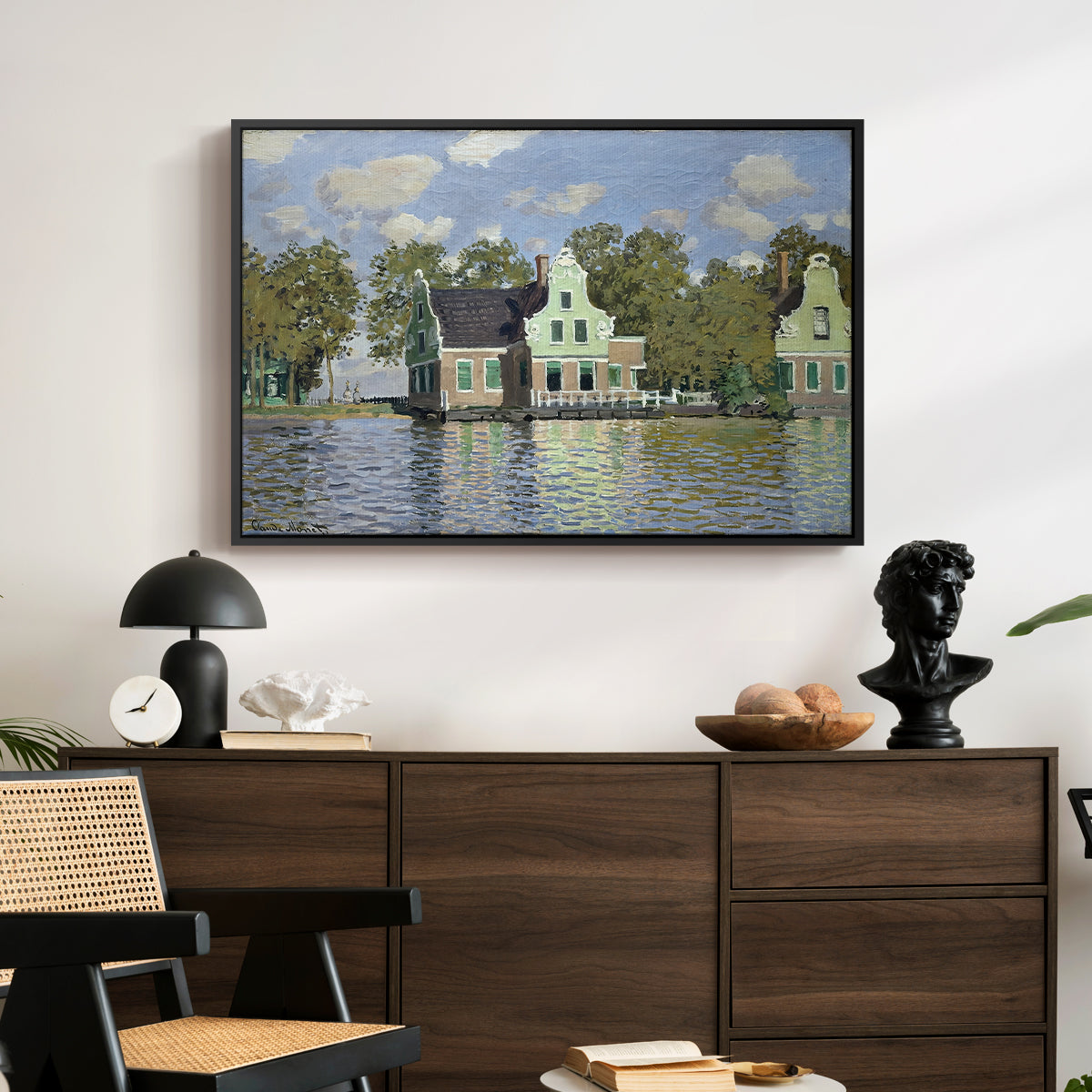 Houses on the Zaan River at Zaandam, 1871 by Claude Monet displayed in a black floater framed canvas above a dark wood credenza in an entryway.