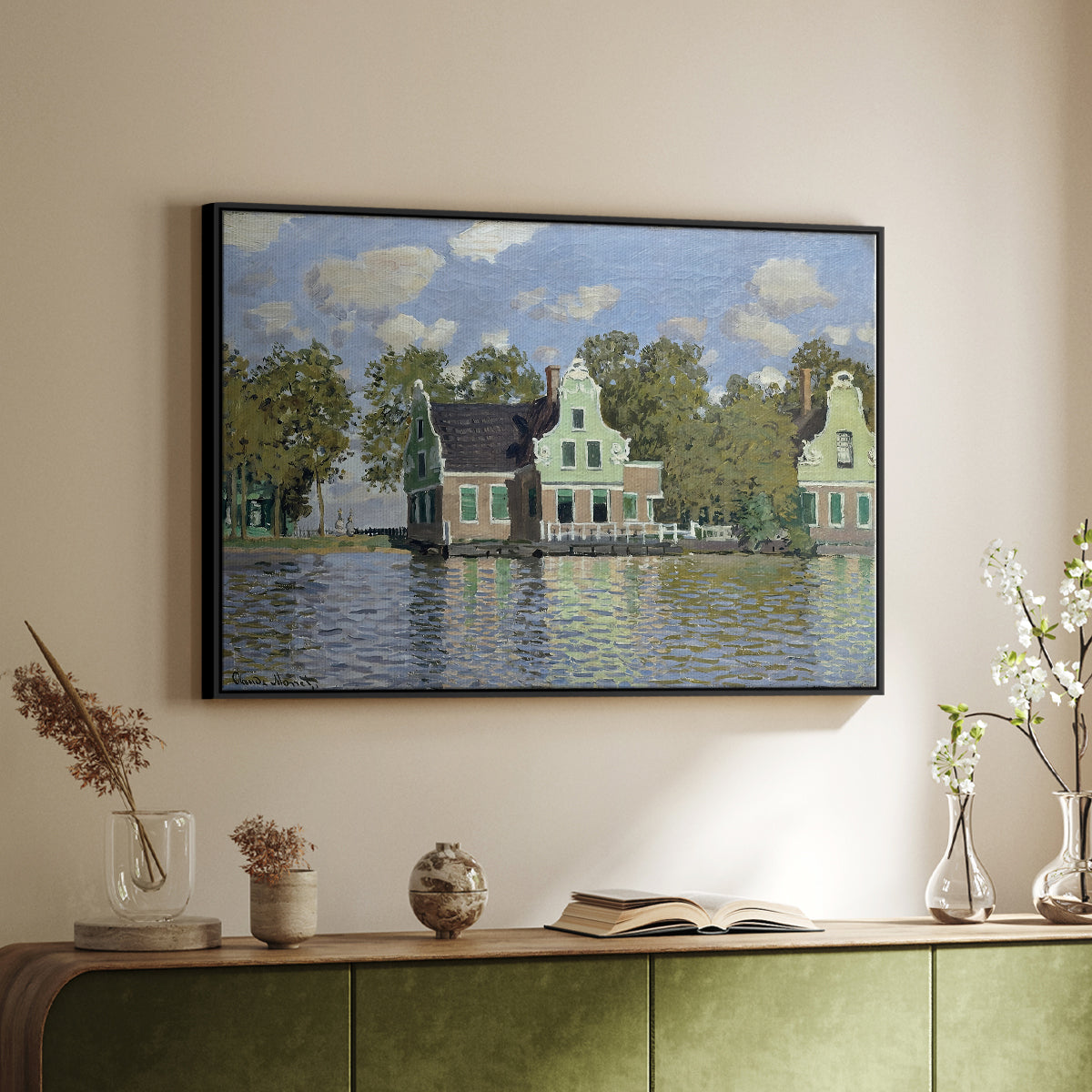 Black floater framed canvas of Houses on the Zaan River at Zaandam, 1871 by Claude Monet, featuring an impressionist riverside village with colorful buildings above a sideboard in a softly lit hallway.