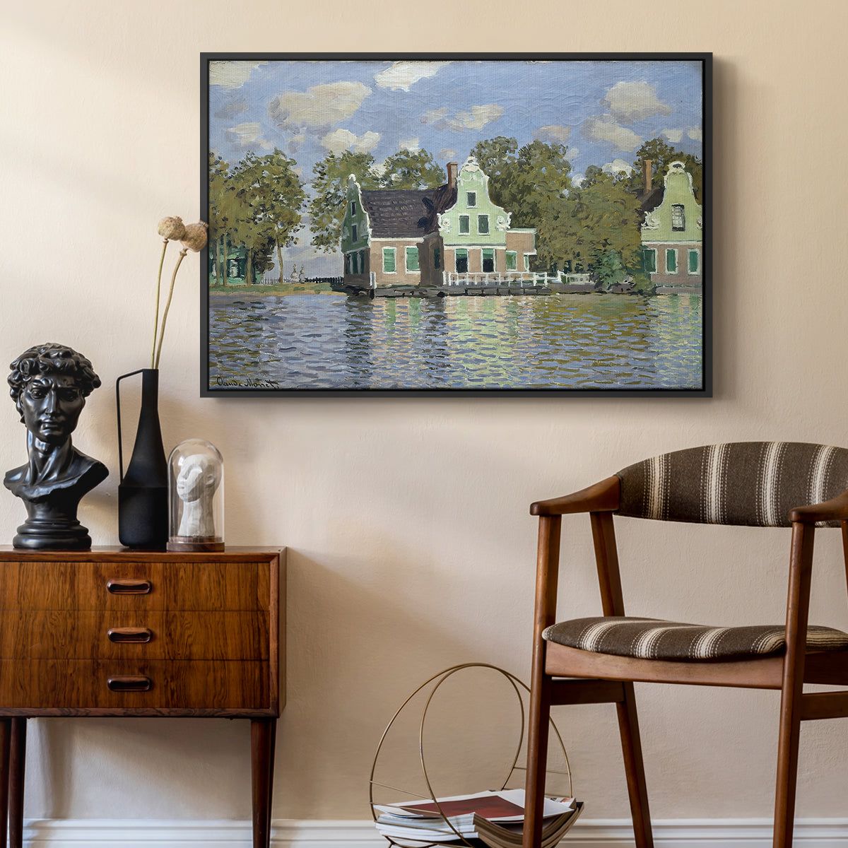 Houses on the Zaan River at Zaandam, 1871 by Claude Monet as a black floater framed canvas featuring a peaceful canal scene with houses mirrored in water, styled above a mid-century console in a contemporary living area.