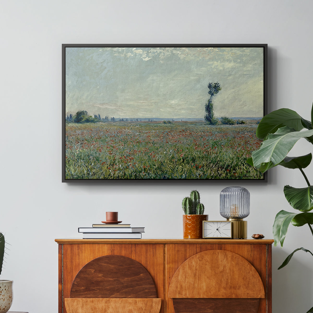 Poppy Field, 1881 by Claude Monet in a black floater framed canvas featuring a wide field of red poppies stretching across countryside under open sky, displayed above a wood console cabinet.