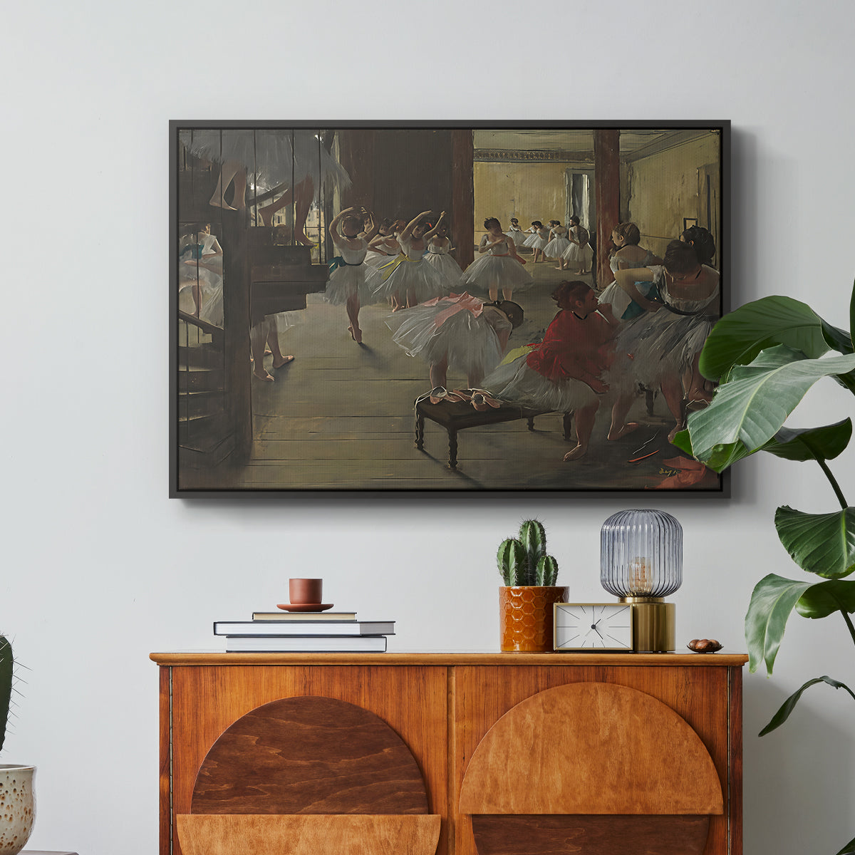 The Dance Class, c. 1873 by Edgar Degas in a black floater framed canvas featuring ballerinas practicing in studio with instructor observing nearby, displayed above a wood console cabinet.