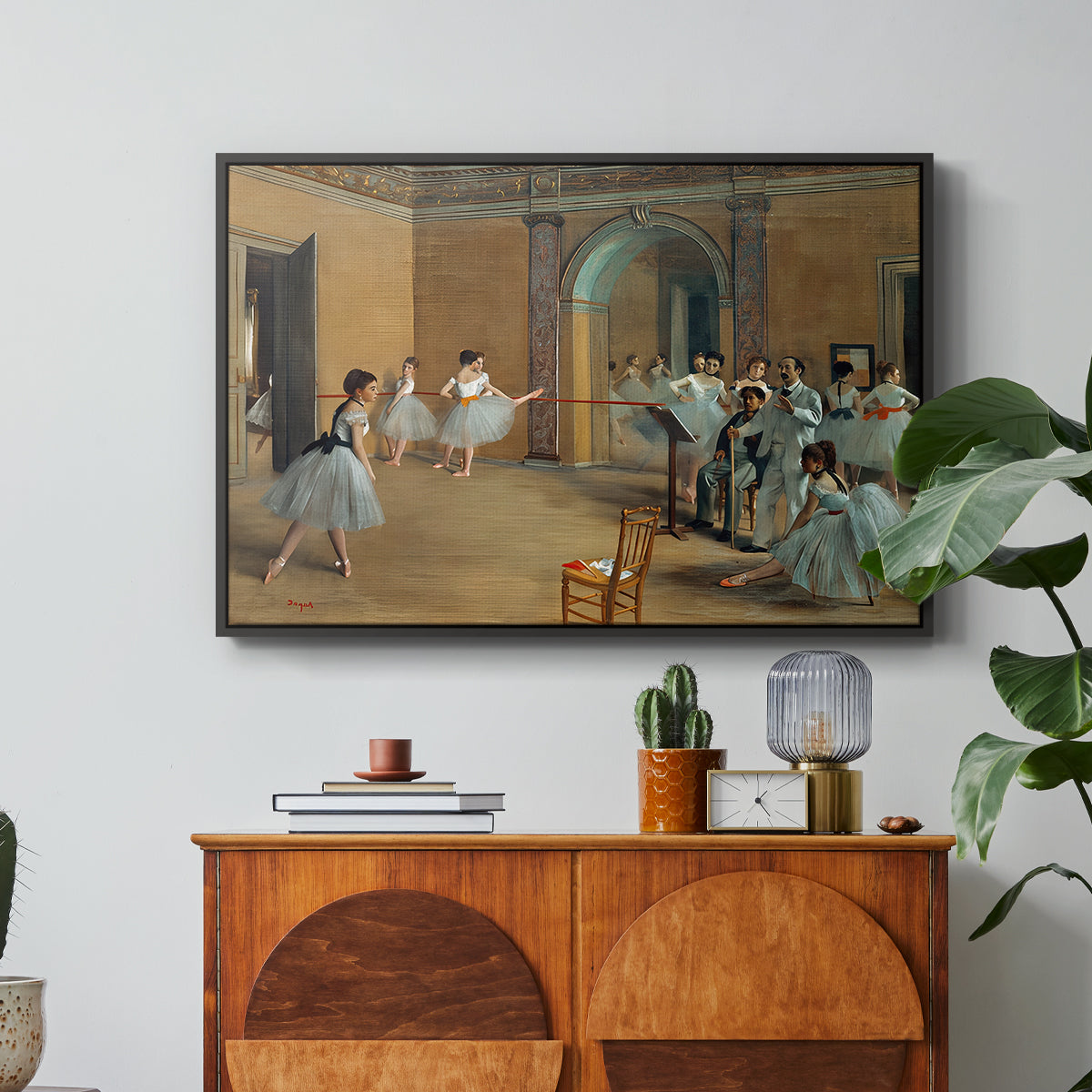 The Dance Foyer at the Opera on the Rue Le Peletier, 1872 by Edgar Degas in a black floater framed canvas featuring ballet dancers gathered in rehearsal hall with mirrors and columns, displayed above a wood console cabinet.