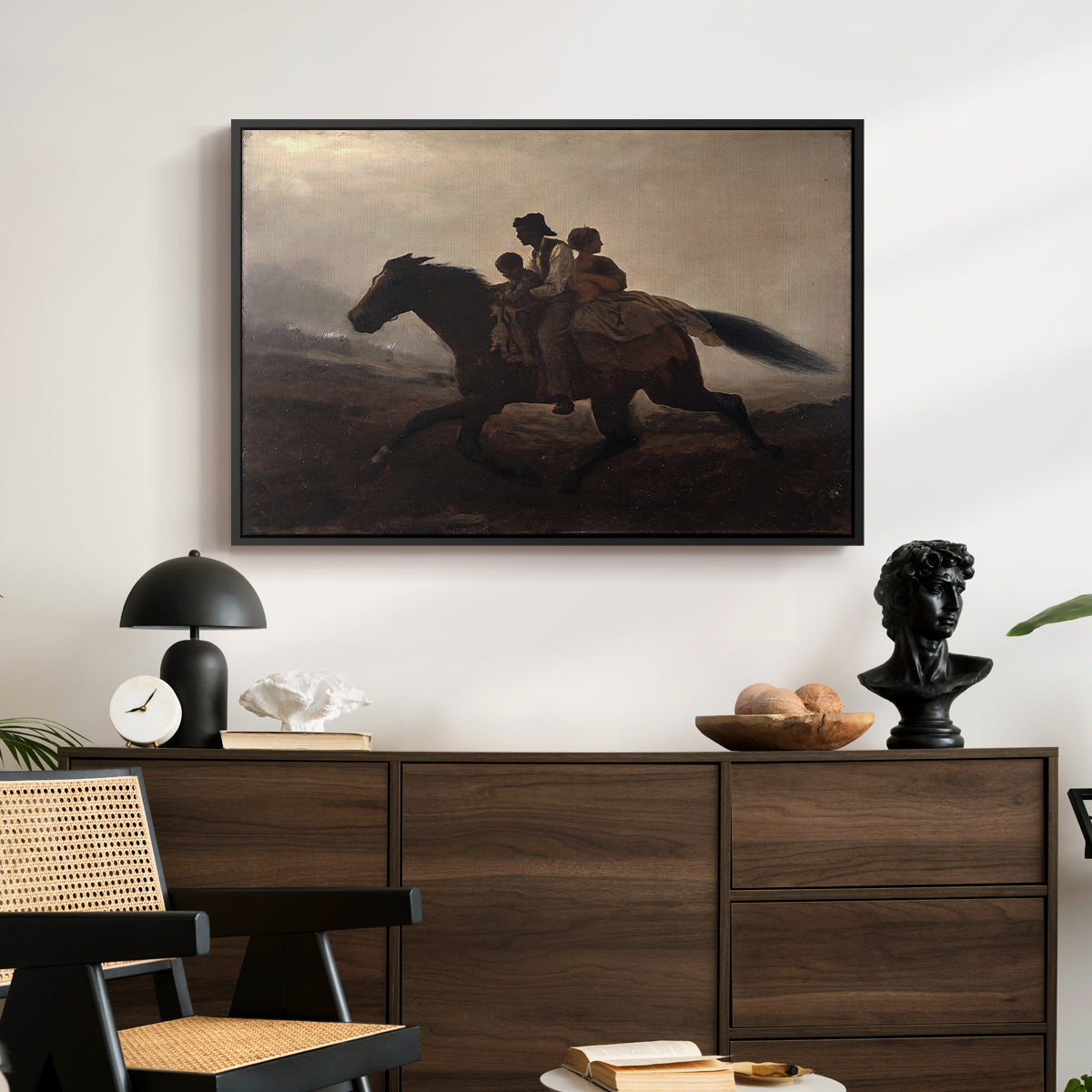 A Ride for Liberty – The Fugitive Slaves, c. 1862 by Eastman Johnson displayed in a black floater framed canvas above a dark wood credenza in an entryway.
