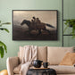 Black floater framed canvas featuring figures on horse moving swiftly through shadowy landscape, displayed above a sofa in a modern living room.
