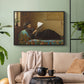 Black floater framed canvas featuring a casual gathering around newspaper in rustic room, displayed above a sofa in a modern living room.