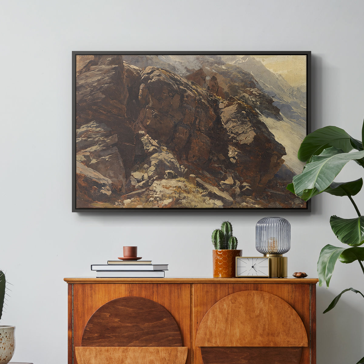 High Mountain Study, c. 1870 by Edward Theodore Compton in a black floater framed canvas featuring a rocky alpine terrain with steep slopes and distant mountain peaks, displayed above a wood console cabinet.