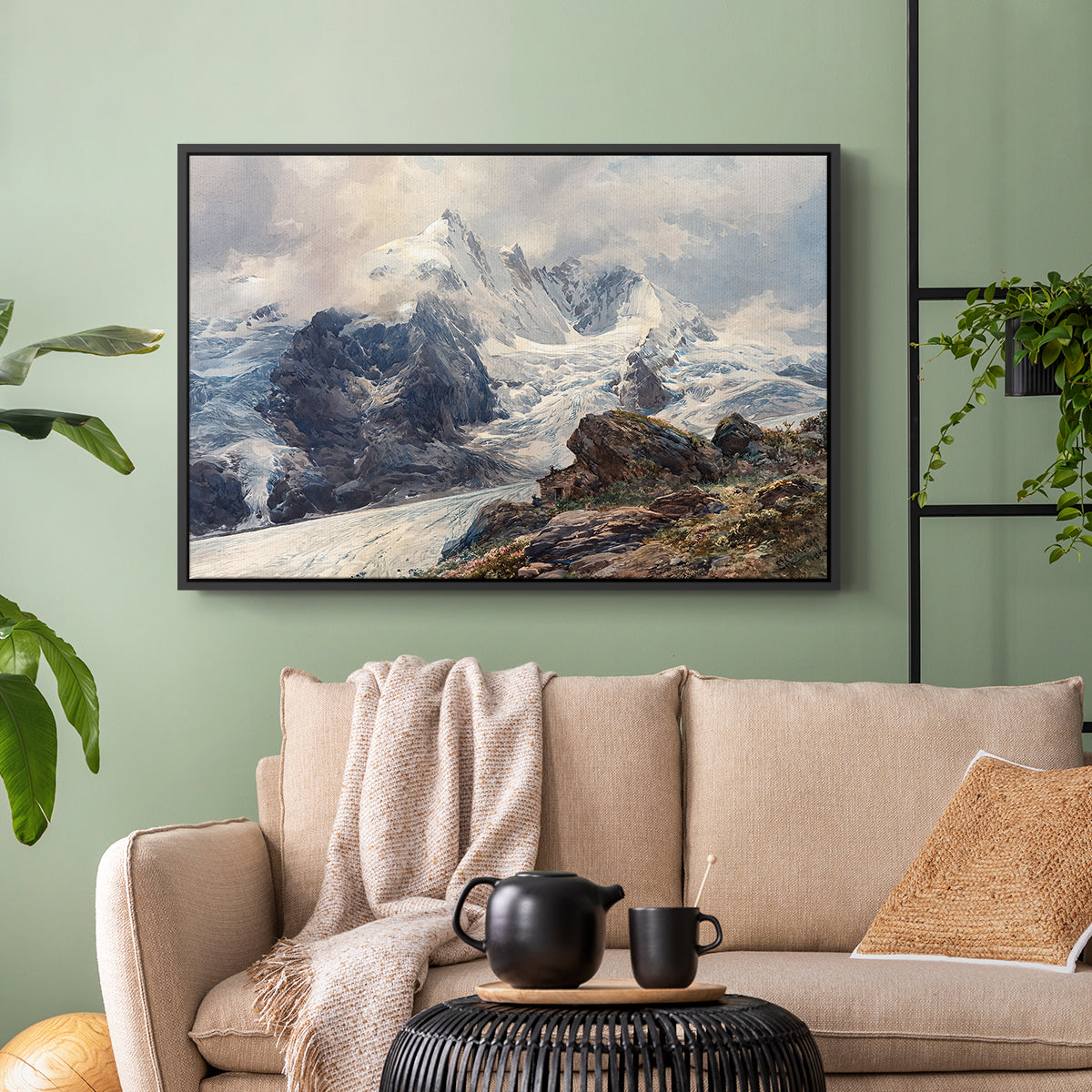 Black floater framed canvas featuring an alpine peak dominating surrounding terrain, displayed above a sofa in a modern living room.