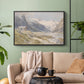 Black floater framed canvas featuring a natural landscape with human presence among mountains, displayed above a sofa in a modern living room.