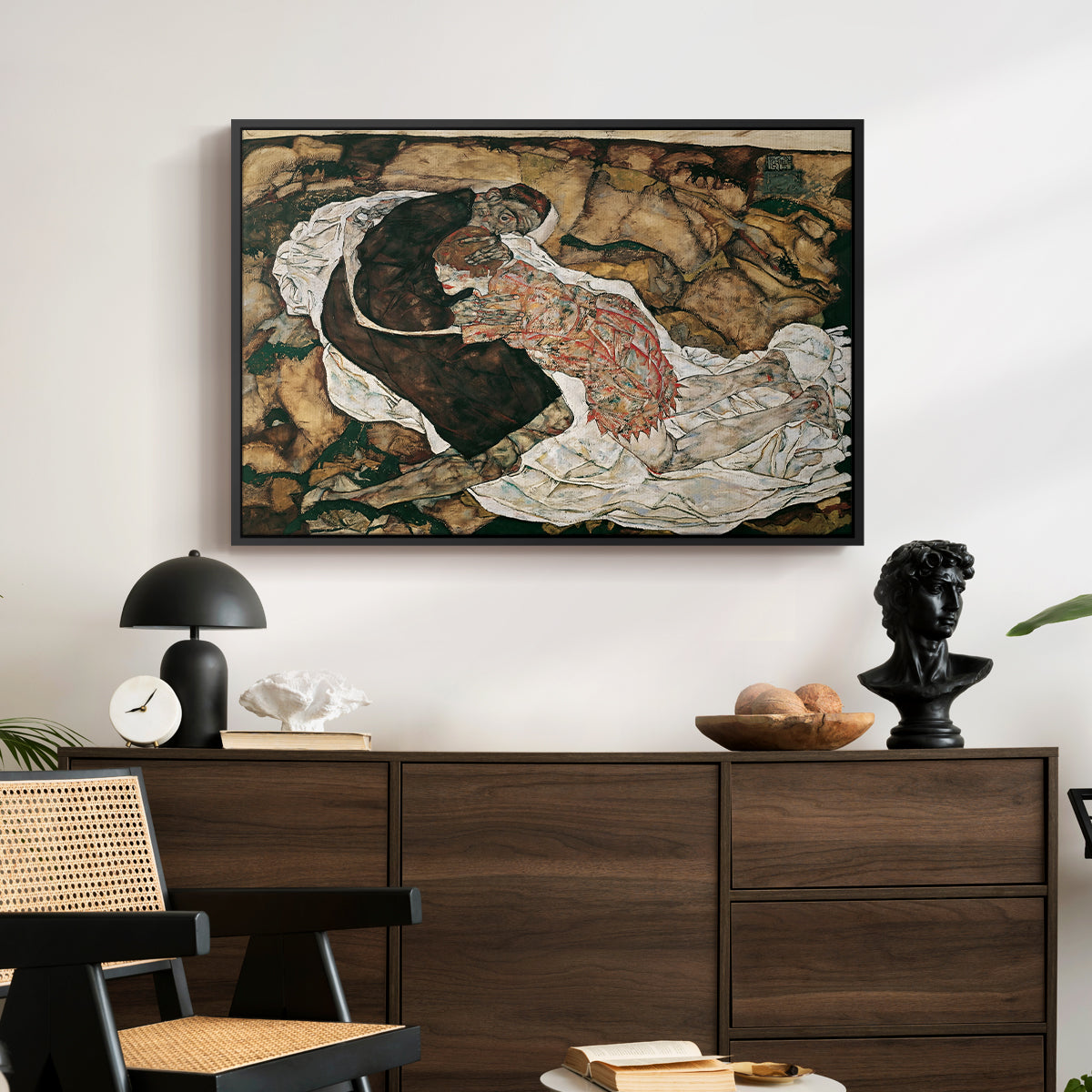 Death and the Maiden, 1915 by Egon Schiele displayed in a black floater framed canvas above a dark wood credenza in an entryway.