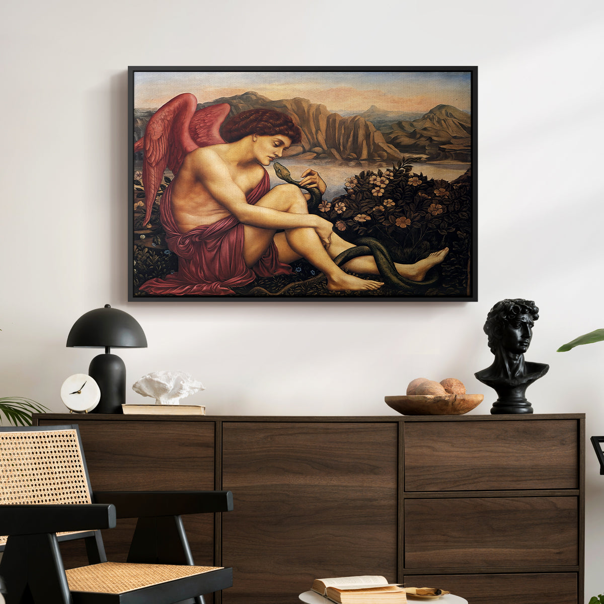 The Angel with the Serpent, c. 1870-1875 by Evelyn De Morgan displayed in a black floater framed canvas above a dark wood credenza in an entryway.