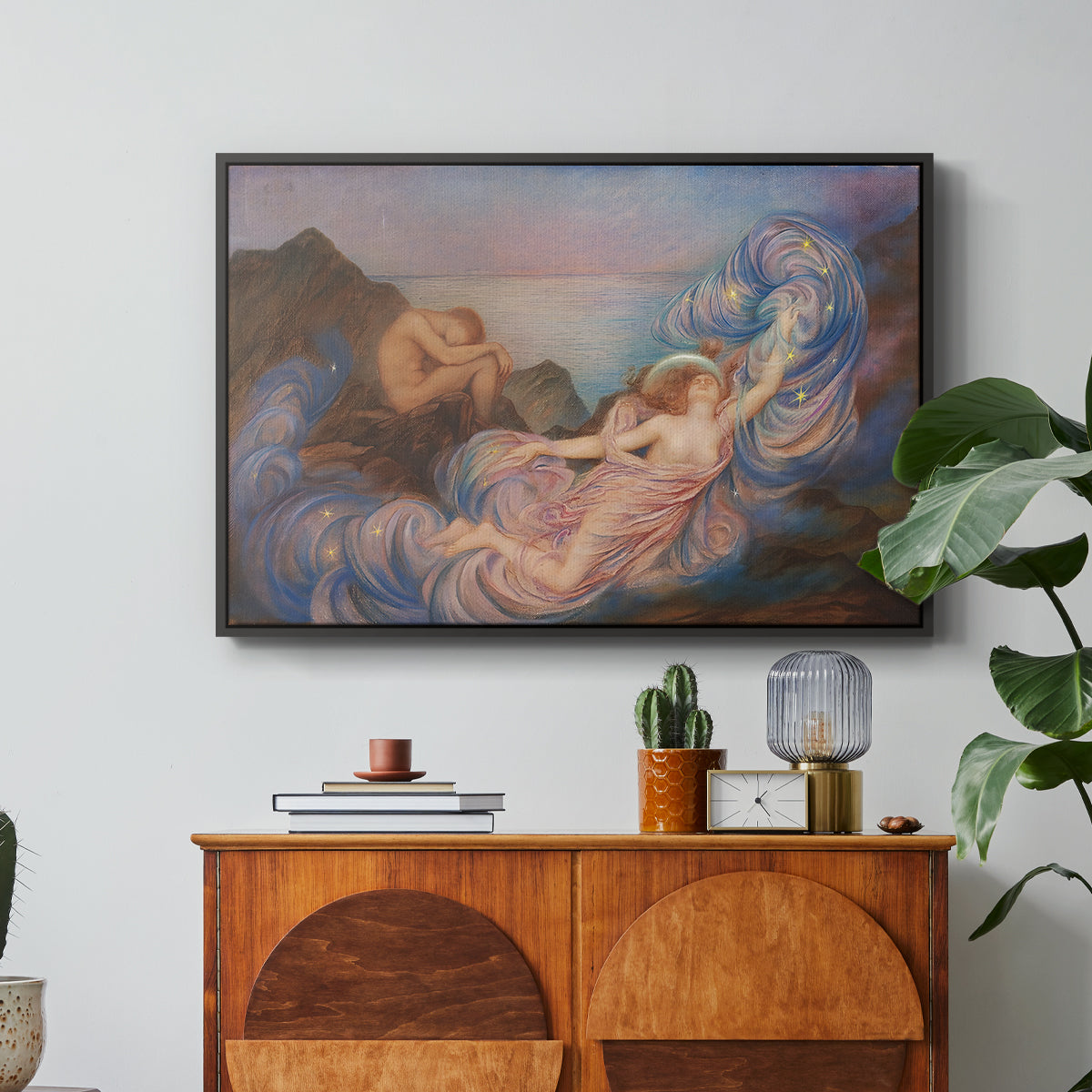 Twilight, 1914 by Evelyn De Morgan in a black floater framed canvas featuring a reclining female figure beneath glowing sky at twilight with soft colors, displayed above a wood console cabinet.
