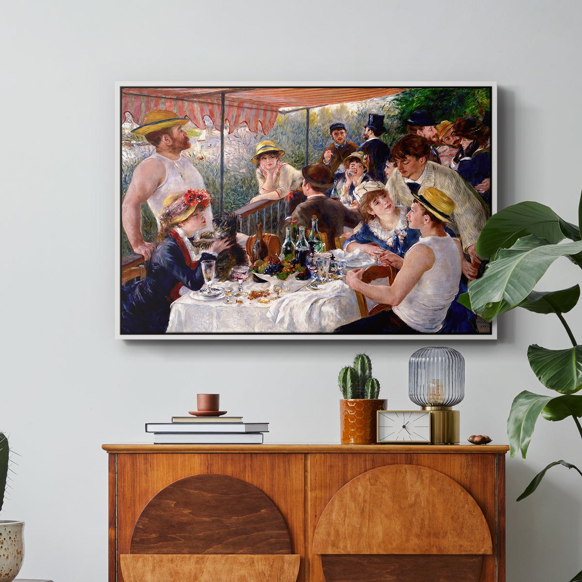 Luncheon of the Boating Party (Le Déjeuner des canotiers), 1880-1881 by Pierre-Auguste Renoir in a white floater framed canvas featuring a group of elegantly dressed people dining together on a sunlit balcony overlooking the river, displayed above a wood console cabinet.