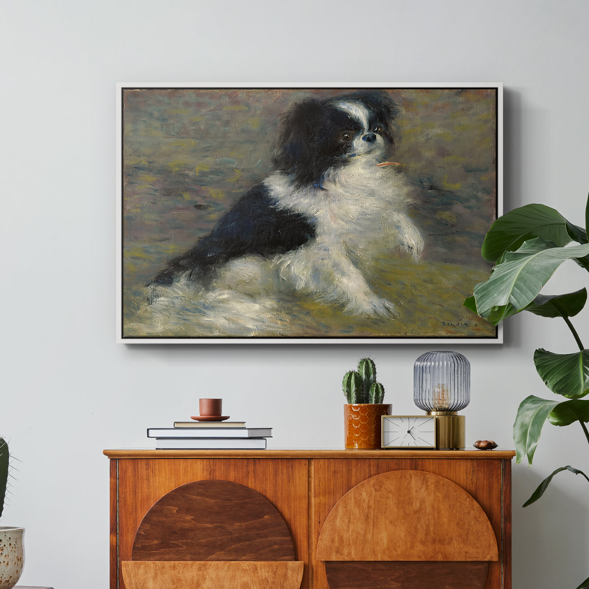 Tama, the Japanese Dog, c. 1876 by Pierre-Auguste Renoir in a white floater framed canvas featuring a small black and white dog standing in shallow water with soft brushstrokes, displayed above a wood console cabinet.