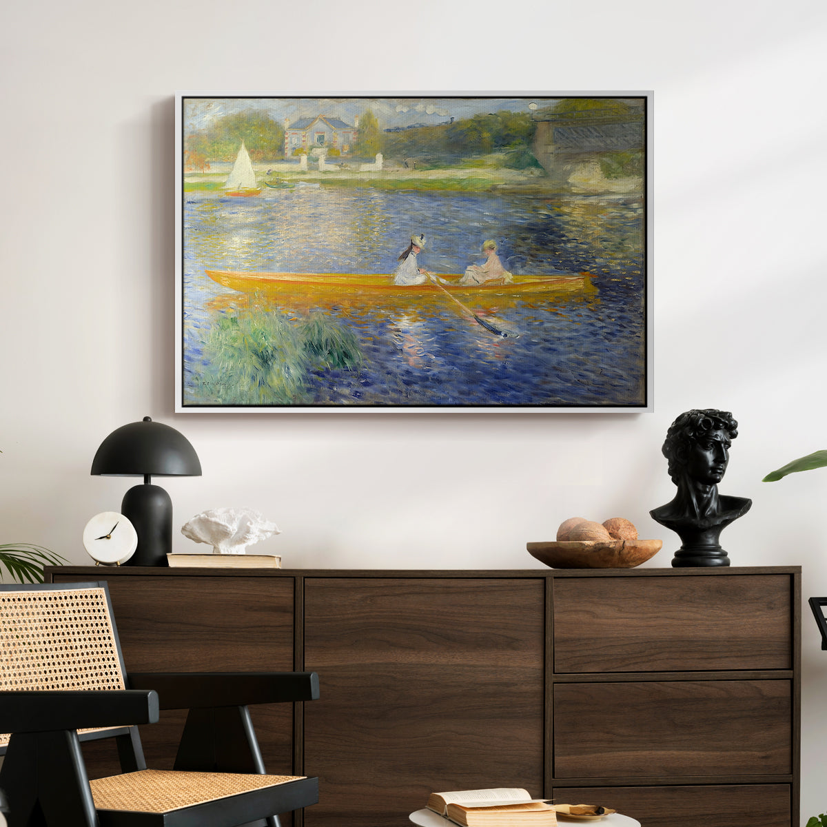 The Skiff (La Yole), 1875 by Pierre-Auguste Renoir displayed in a white floater framed canvas above a dark wood credenza in an entryway.