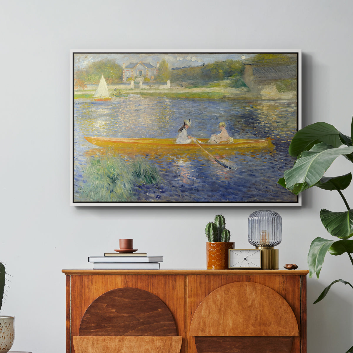 The Skiff (La Yole), 1875 by Pierre-Auguste Renoir in a white floater framed canvas featuring two figures seated in a small boat drifting across calm water, displayed above a wood console cabinet.