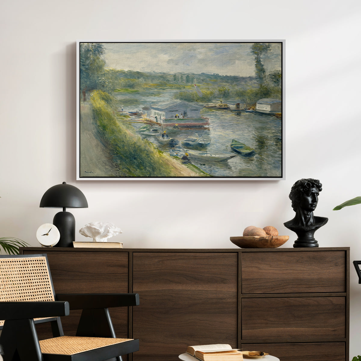 Wash-House Boat at Bas-Meudon, c. 1874 by Pierre-Auguste Renoir displayed in a white floater framed canvas above a dark wood credenza in an entryway.