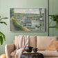 White floater framed canvas featuring an everyday life scene with boat and figures along river edge, displayed above a sofa in a modern living room.