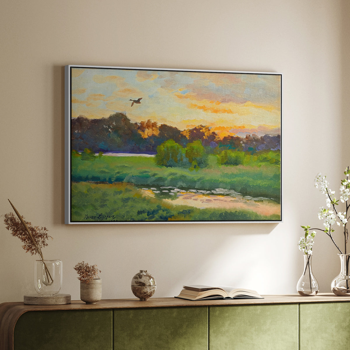 White floater framed canvas of Flying Duck at Sunset, 1924 by Bruno Liljefors, featuring a lone duck soaring over a glowing marshland above a sideboard in a softly lit hallway.