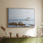 White floater framed canvas of Greylag Geese (Grågäss), 1922 by Bruno Liljefors, featuring birds standing and resting along shoreline with soft grass and water above a sideboard in a softly lit hallway.