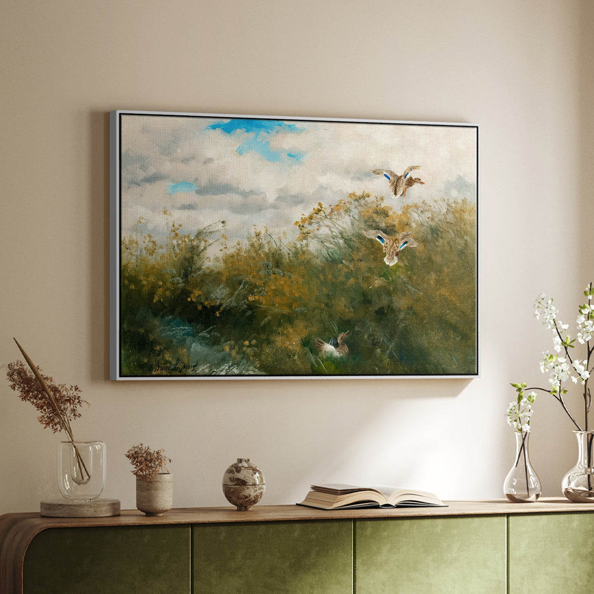 White floater framed canvas of Wild Ducks (Grasänder), 1890 by Bruno Liljefors, featuring a wildlife scene of ducks walking through tall grass beside water above a sideboard in a softly lit hallway.