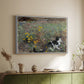 White floater framed canvas of Cat on a Flowery Meadow, 1887 by Bruno Liljefors, featuring a small cat resting among colorful flowers in grassy field above a sideboard in a softly lit hallway.