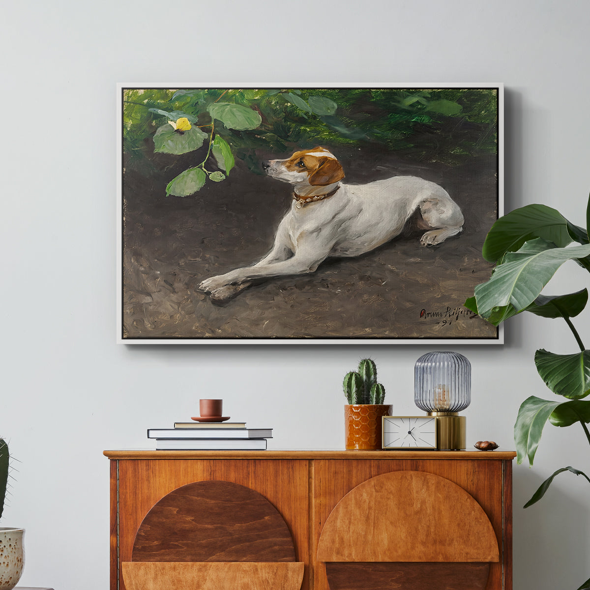 Portrait of a Dog, 1891 by Bruno Liljefors in a white floater framed canvas featuring a dog lying on ground with head raised in natural outdoor setting, displayed above a wood console cabinet.