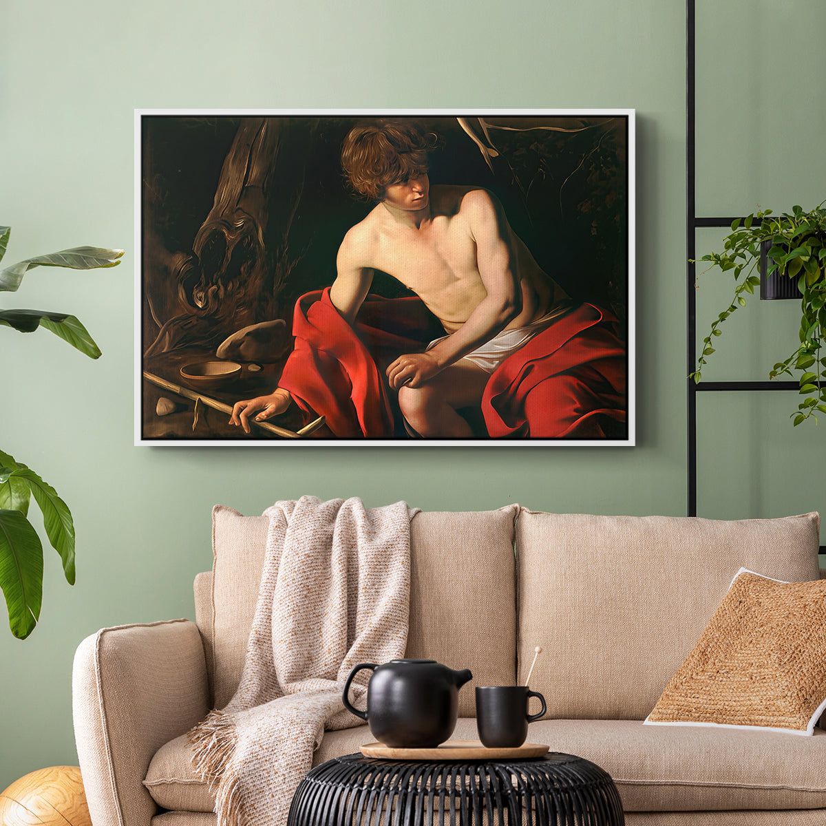 White floater framed canvas featuring a contemplative religious figure in rustic wilderness environment, displayed above a sofa in a modern living room.