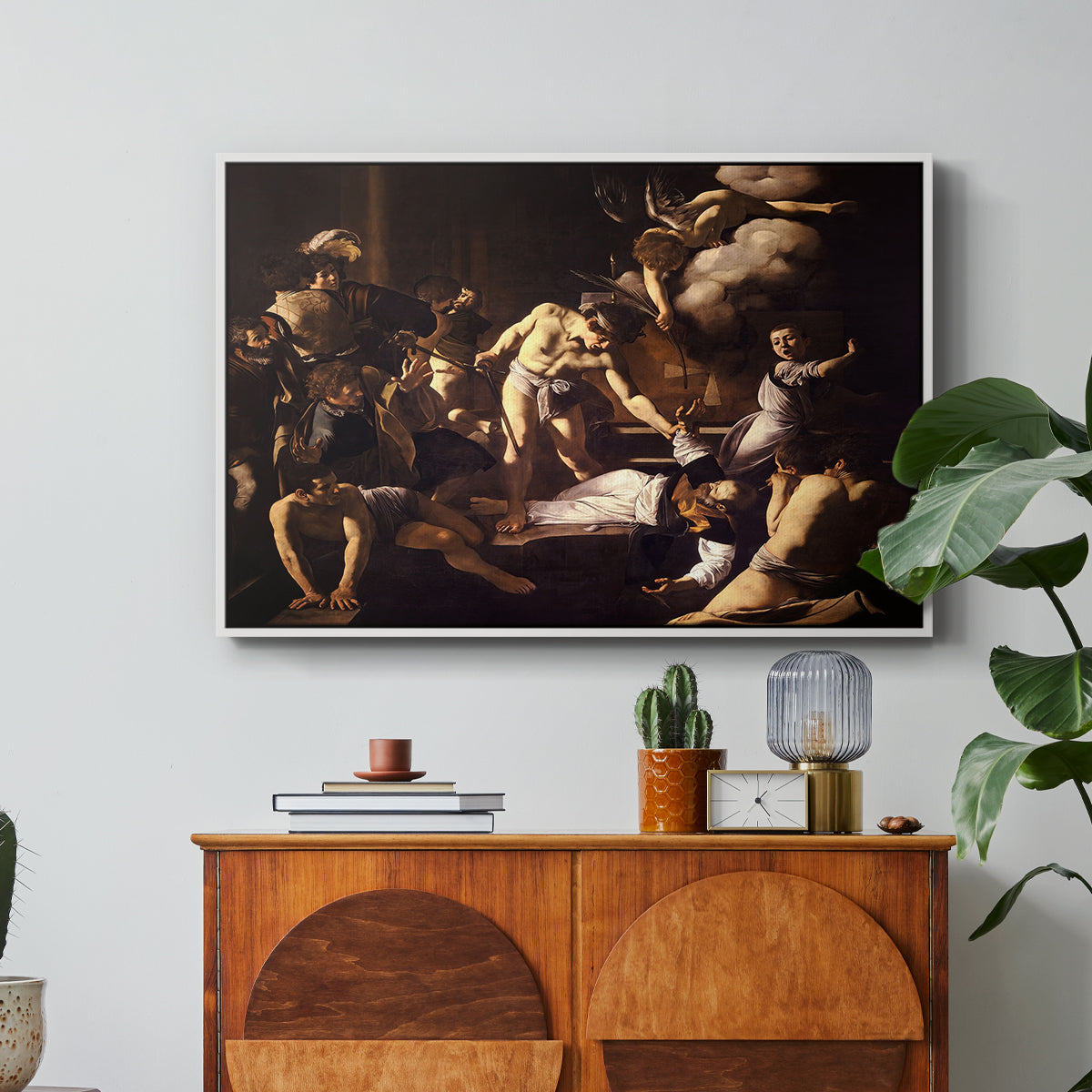 The Martyrdom of Saint Matthew, 1599-1600 by Caravaggio in a white floater framed canvas featuring a chaotic scene of Saint Matthew being attacked by executioner in church, displayed above a wood console cabinet.