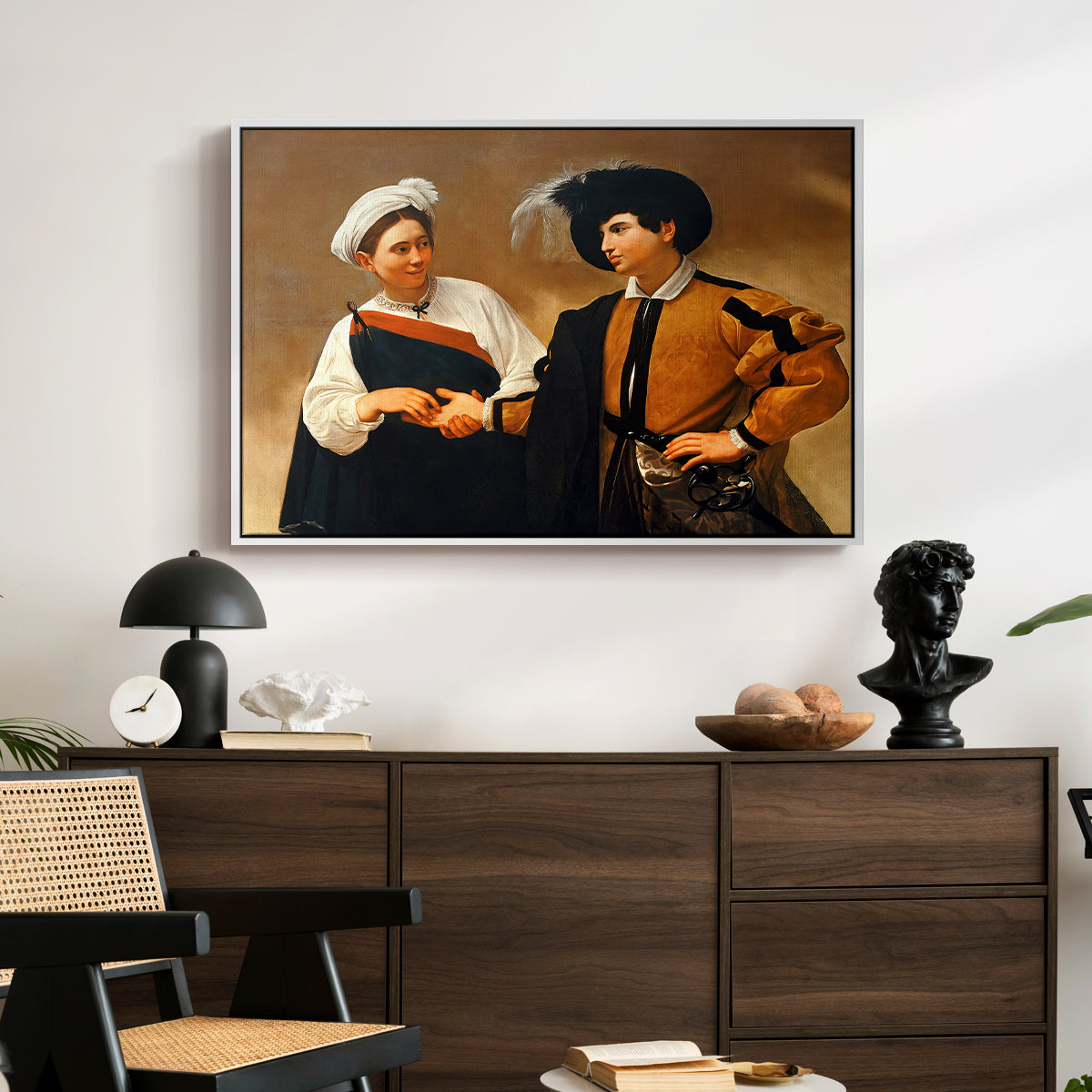 The Fortune Teller (Capitoline Version), c. 1599 by Caravaggio displayed in a white floater framed canvas above a dark wood credenza in an entryway.