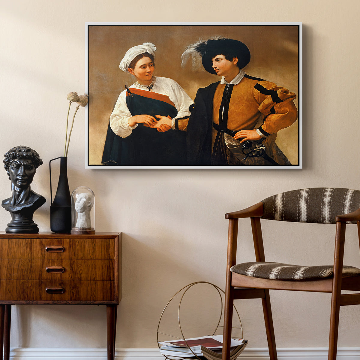 The Fortune Teller (Capitoline Version), c. 1599 by Caravaggio as a white floater framed canvas featuring a close interaction between two figures involving deception and gesture, styled above a mid-century console in a contemporary living area.