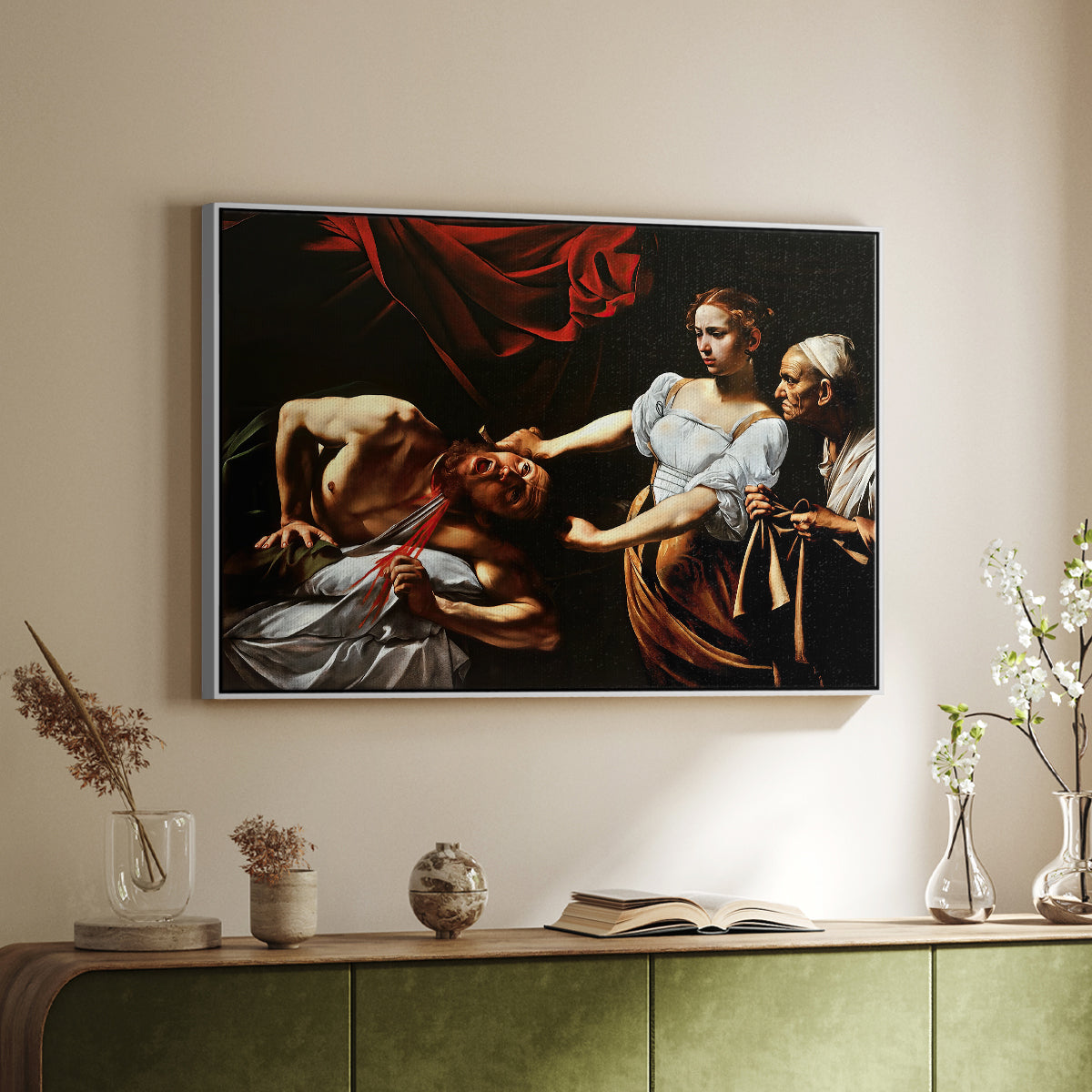 White floater framed canvas of Judith Beheading Holofernes, c. 1599 by Caravaggio, featuring a dramatic biblical scene of woman beheading man in bed above a sideboard in a softly lit hallway.