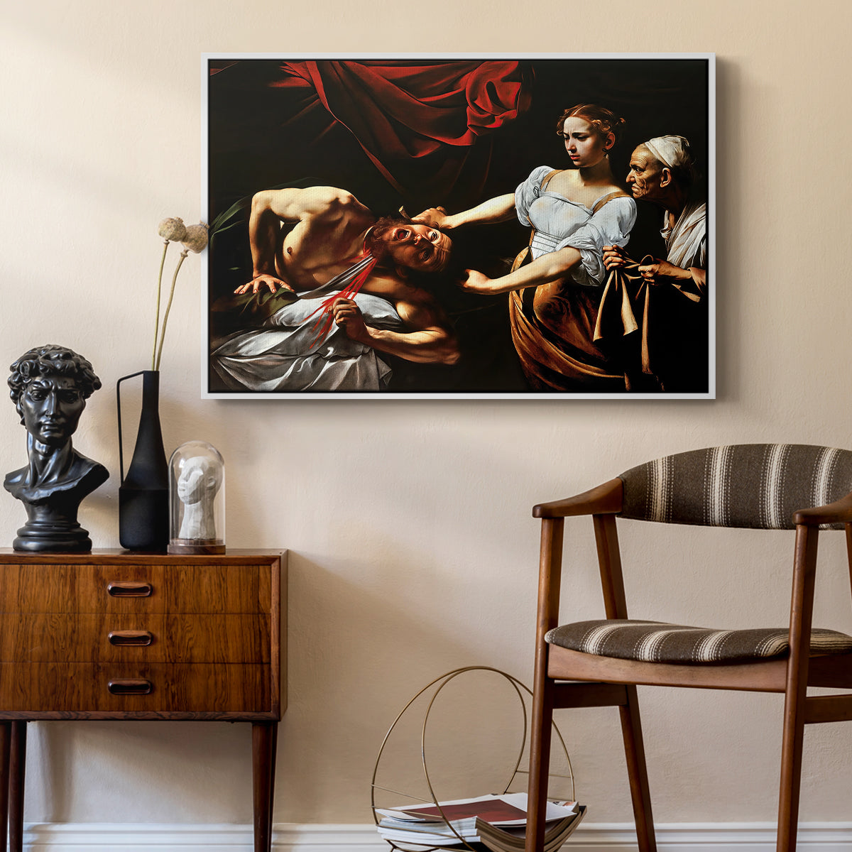Judith Beheading Holofernes, c. 1599 by Caravaggio as a white floater framed canvas featuring an intense moment of Judith slaying Holofernes with sword, styled above a mid-century console in a contemporary living area.