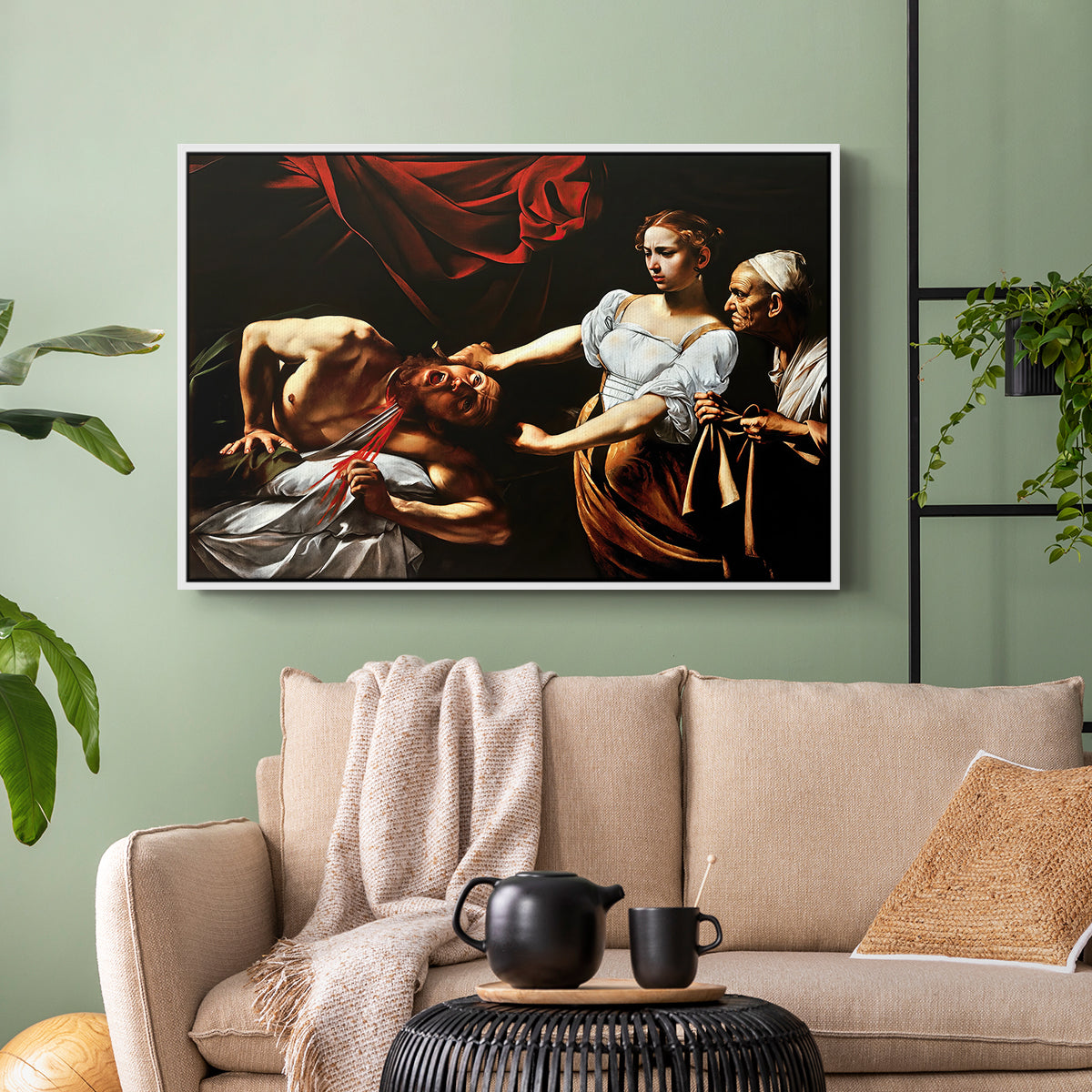 White floater framed canvas featuring a violent religious narrative with strong contrast of light and shadow, displayed above a sofa in a modern living room.