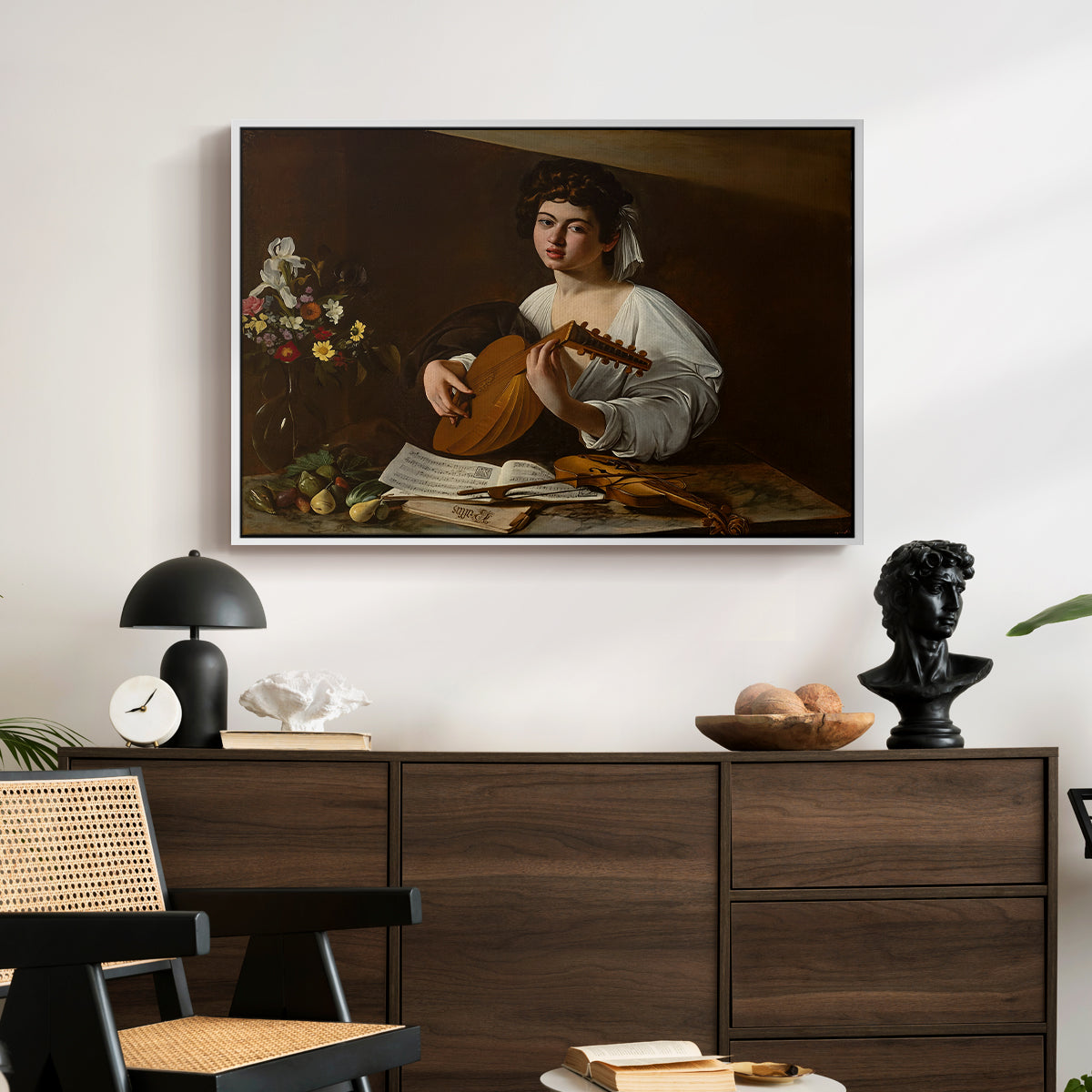 The Lute Player (Hermitage Version), c. 1596 by Caravaggio displayed in a white floater framed canvas above a dark wood credenza in an entryway.