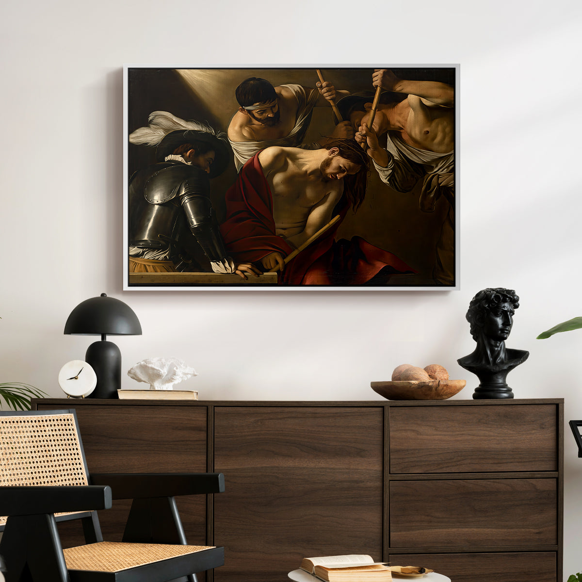 The Crowning with Thorns (Vienna Version), c. 1602-1604 by Caravaggio displayed in a white floater framed canvas above a dark wood credenza in an entryway.