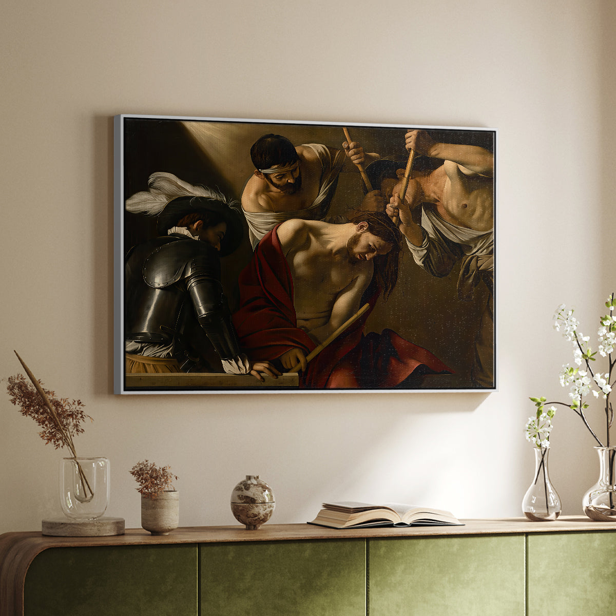 White floater framed canvas of The Crowning with Thorns (Vienna Version), c. 1602-1604 by Caravaggio, featuring a biblical scene of Christ being mocked and crowned with thorns above a sideboard in a softly lit hallway.