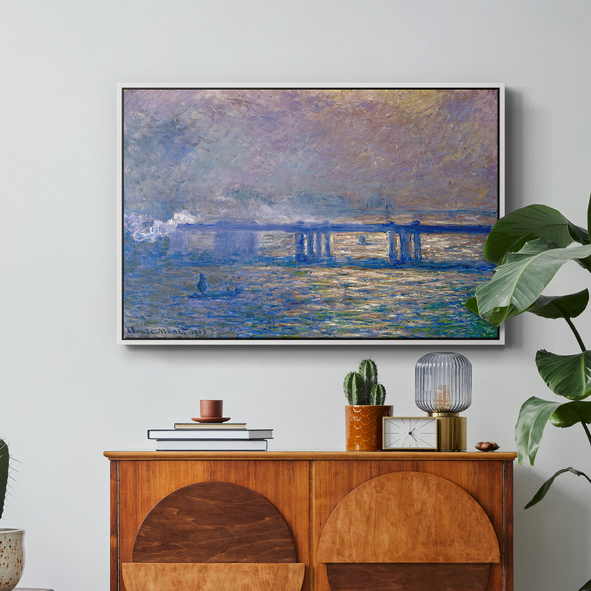 Charing Cross Bridge, 1903 by Claude Monet in a white floater framed canvas featuring an impressionist view of bridge stretching across river with soft light and haze, displayed above a wood console cabinet.