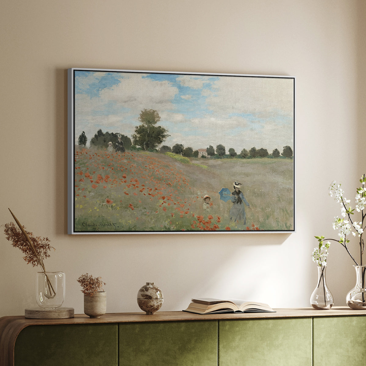 White floater framed canvas of The Poppy Field near Argenteuil, 1873 by Claude Monet, featuring an impressionist countryside scene with flowers and strolling figures above a sideboard in a softly lit hallway.