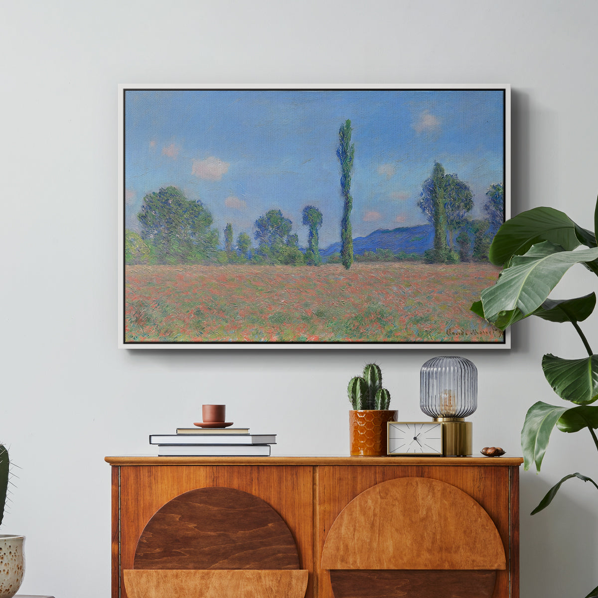 Poppy Field (Giverny), 1890-1891 by Claude Monet in a white floater framed canvas featuring an expansive field of red poppies with tall trees under blue sky, displayed above a wood console cabinet.