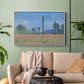 White floater framed canvas featuring a rural field filled with red blossoms beneath open sky, displayed above a sofa in a modern living room.